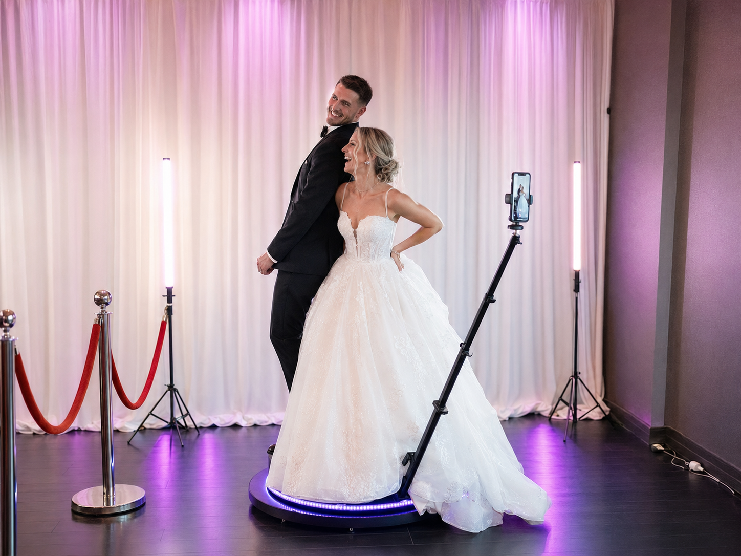 Bride and groom posing on a 360 photo booth platform